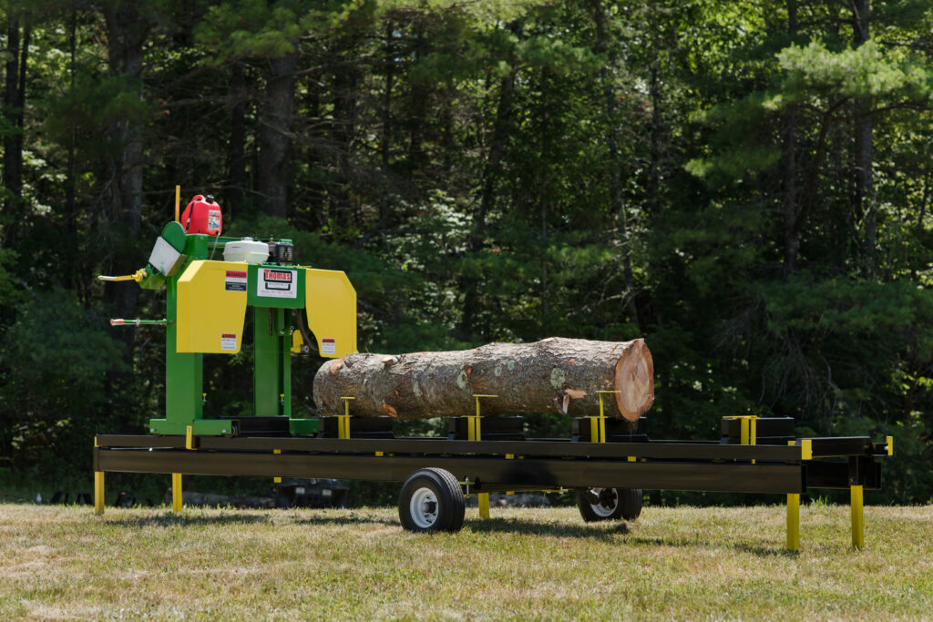 A log on the back of a trailer with a tractor in front.